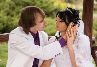 iki aşk gelin ve damat tahta bankta oturmuş poz içinde