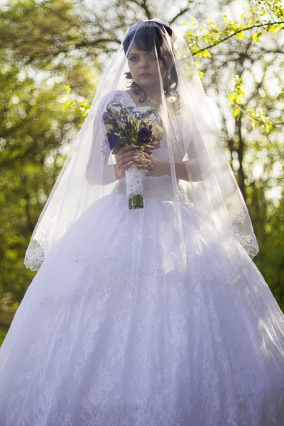 The bride is closed veil with a bouquet in hand — Stock Photo, Image