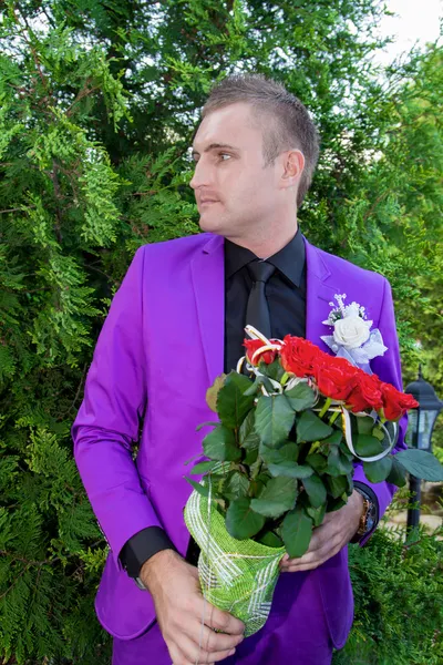 Bir buket çiçek tutan genç gülümseyen adam — Stok fotoğraf