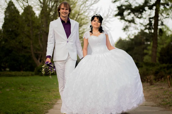 Felice sposa e lo sposo in vicolo ombreggiato sulla passeggiata nuziale — Foto Stock