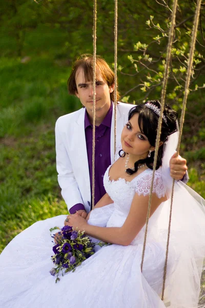 Bride and groom swinging on a swing — Stock Photo, Image