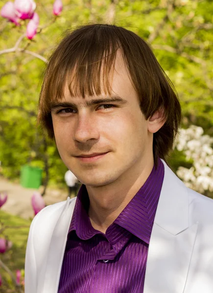 Thoughtful guy in the park a white suit and purple shirt — Stock Photo, Image