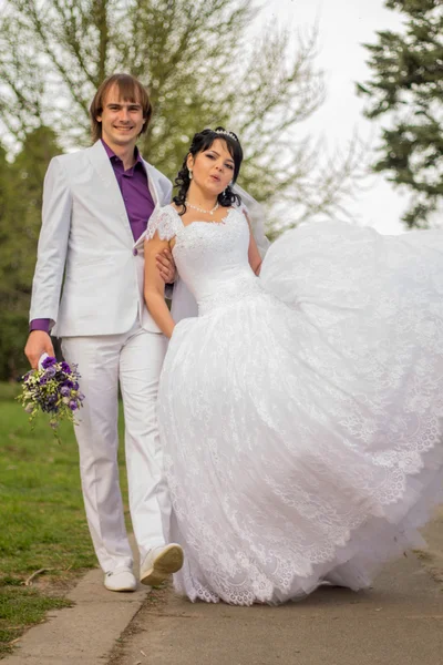 Happy bride and groom in shady alley on wedding walk — Stock Photo, Image