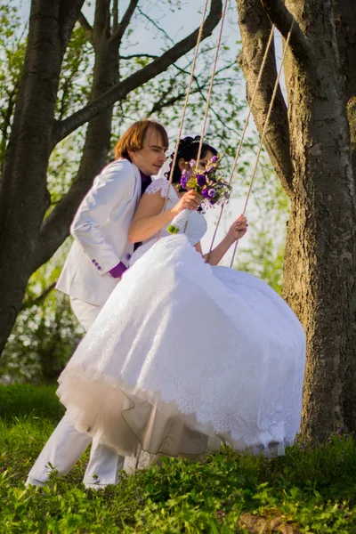 Noiva e noivo balançando em um balanço — Fotografia de Stock