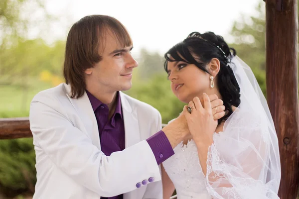 Casal apaixonado noiva e noivo posando sentado no banco de madeira em — Fotografia de Stock