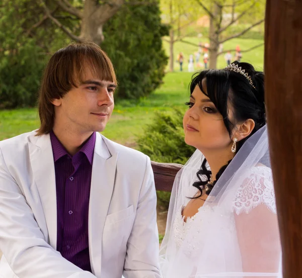 Coppia innamorata sposa e sposo in posa seduta su panca di legno in — Foto Stock