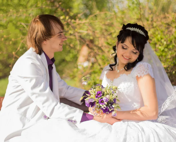 Romantic wedding couple sitting on a bench in the park — Stock Photo, Image