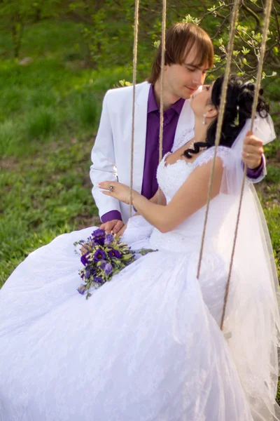 Bride and groom swinging on a swing — Stock Photo, Image