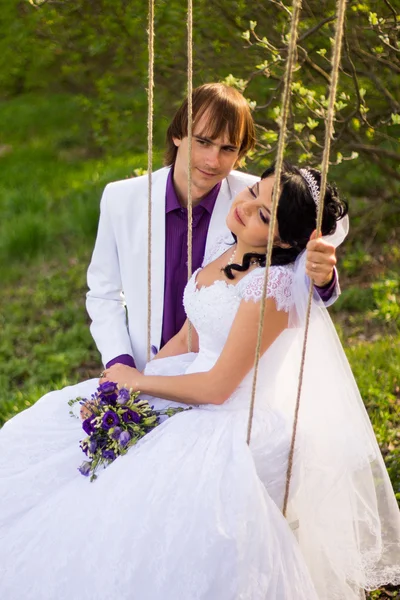 Bride and groom swinging on a swing — Stock Photo, Image