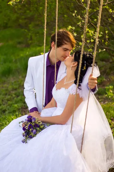 Bride and groom swinging on a swing — Stock Photo, Image