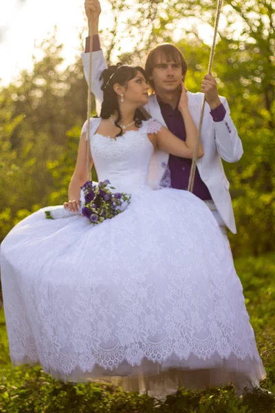 Bride and groom swinging on a swing — Stock Photo, Image