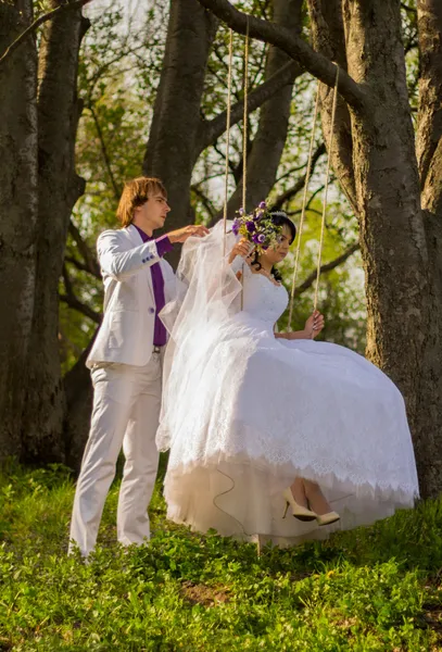 Sposa e sposo oscillante su un altalena — Foto Stock