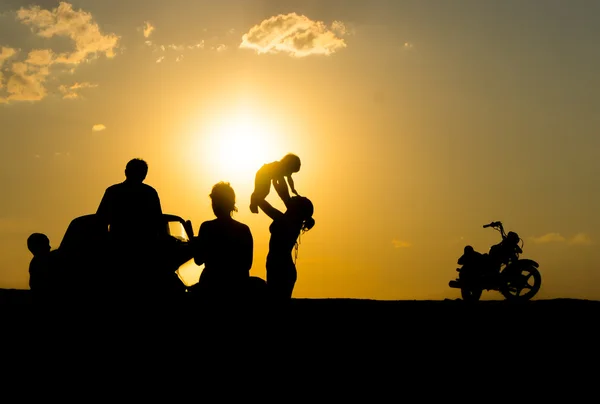 Glückliche Familie von drei Personen, feiern draußen bei Sonnenuntergang, Silhou — Stockfoto
