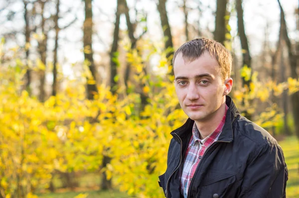 Jovem homem bonito no parque de outono — Fotografia de Stock