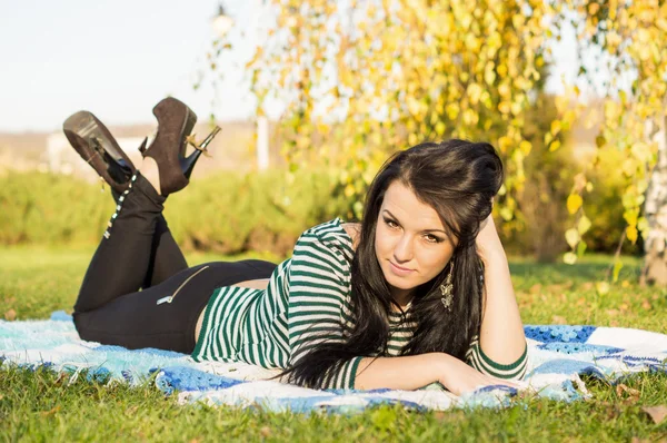 Giovane donna sdraiata a terra nel parco autunnale — Foto Stock