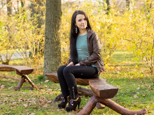 Девушка сидит на скамейке на открытом воздухе — стоковое фото