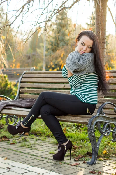 Flicka sitter på bänken utomhus — Stockfoto