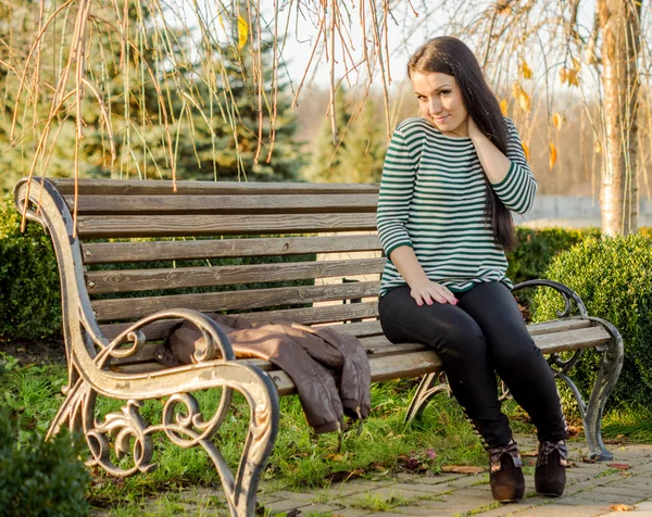 Flicka sitter på bänken utomhus — Stockfoto