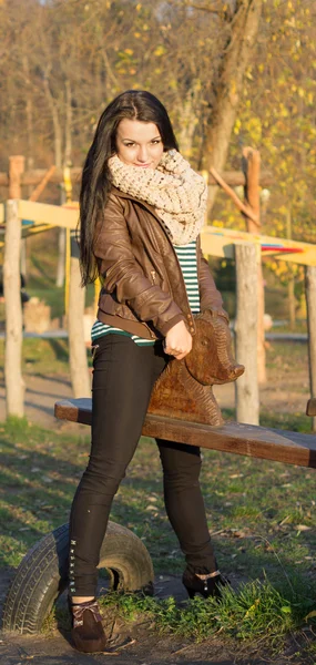 Smiling young model relaxing in a sunny garden sitting on swing — Stock Photo, Image