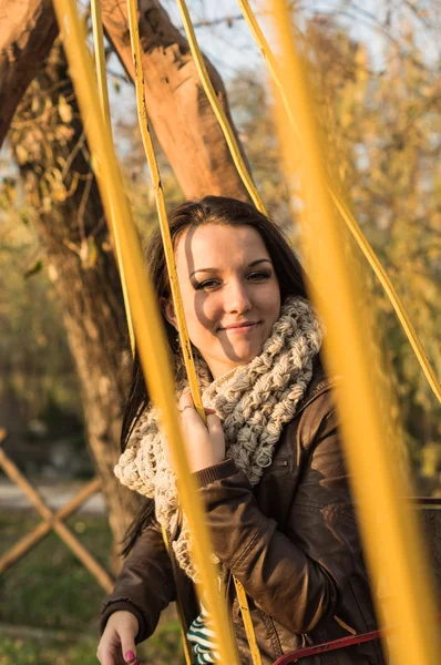 Sonriendo joven modelo relajante en un jardín soleado sentado en el columpio —  Fotos de Stock