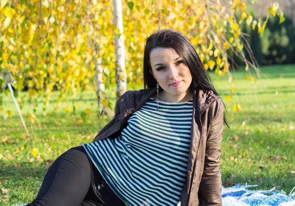 Jonge vrouw vaststelling van op de grond in herfst park — Stockfoto