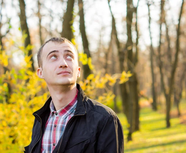 Mladý pohledný muž v podzimním parku — Stock fotografie