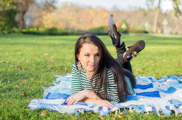 Young woman laying down on the ground in autumn park — Stock Photo, Image