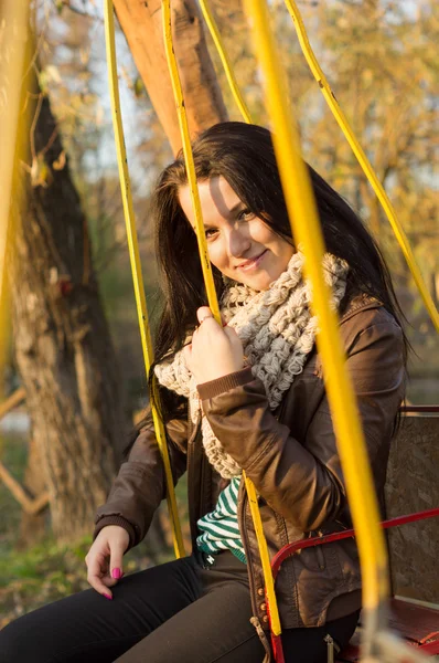 Sonriendo joven modelo relajante en un jardín soleado sentado en el columpio — Foto de Stock