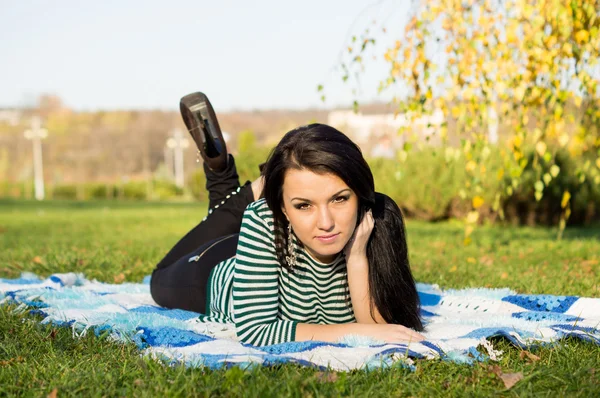 Giovane donna sdraiata a terra nel parco autunnale — Foto Stock