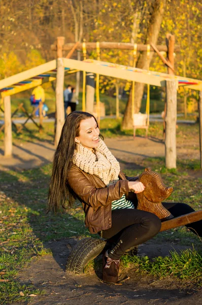Sonriendo joven modelo relajante en un jardín soleado sentado en el columpio — Foto de Stock