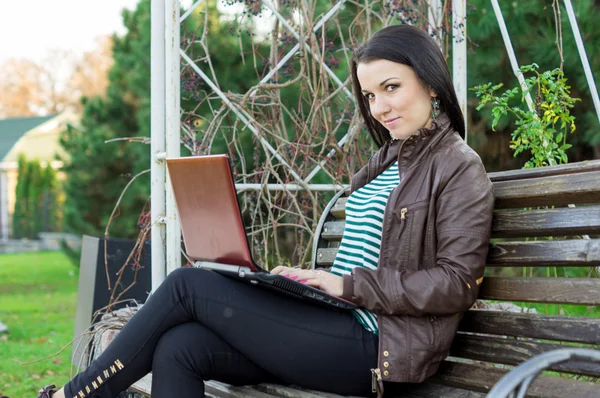 Junge schöne brünette Studentin im Profil sitzt auf Bank über — Stockfoto