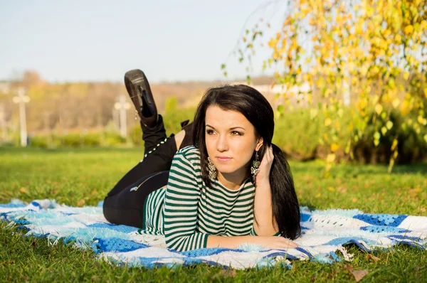 Junge Frau legt sich im Herbstpark auf den Boden — Stockfoto