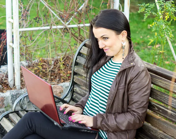 Young beautiful brunette student in profile sits on bench about — Stock Photo, Image