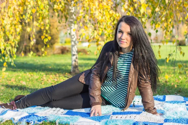 Jonge vrouw vaststelling van op de grond in herfst park — Stockfoto