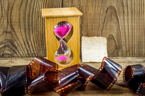 Hourglass and 35mm film with space for text on the wooden backgr — Stock Photo, Image