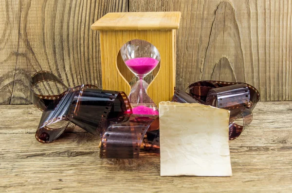 Hourglass and 35mm film with space for text on the wooden backgr — Stock Photo, Image