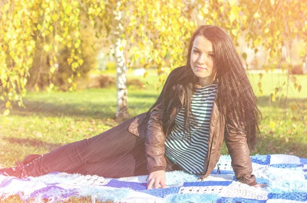 Jonge vrouw vaststelling van op de grond in herfst park — Stockfoto