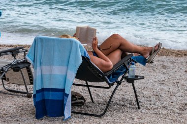 Hırvatistan 'ın Makarska kenti ve sahilde kitap okuyan bir kadın