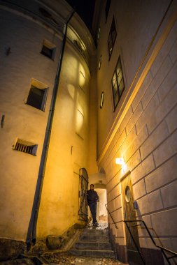 Stockholm, İsveç Geceleri Riddarholmen adasındaki eski binalar Birger Jarl 'ın Kulesi' nin yanında dar bir geçit ve yürüyen bir adam..