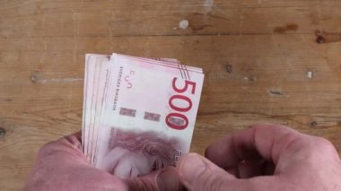 Bir el, bir yığın İsveç 500 kr 'lık banknot dağıtır..