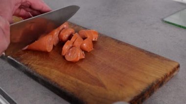 A man slices chorizo sausage on a cutting board.