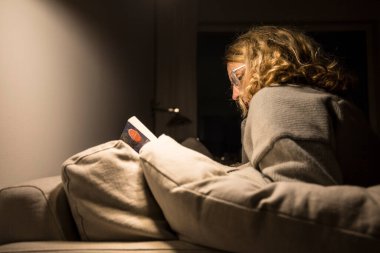 Stockholm, İsveç Bir kadın evinde kanepede kitap okuyor.