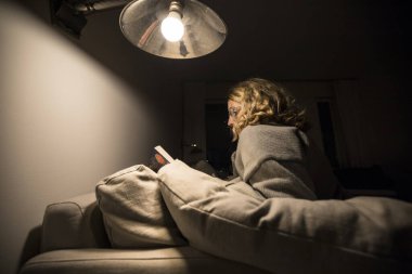 Stockholm, İsveç Bir kadın evinde kanepede kitap okuyor.