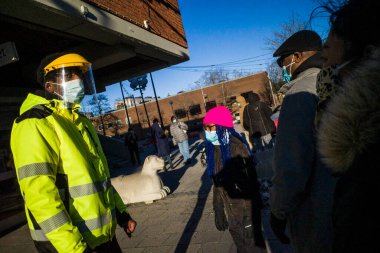 Stockholm, İsveç Bredang banliyösünde maskeli ve vizörlü bir aşı işçisi insanlara PCR testinin dolu olduğunu ve başka test yapılmayacağını söylüyor..