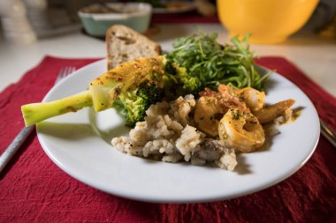 Brokolili bir yemek tabağı, risotto, karides, salata ve ekmek..
