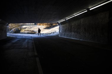 Stockholm, İsveç Bir adam karanlık bir üst geçidin altından ışığa doğru yürür.