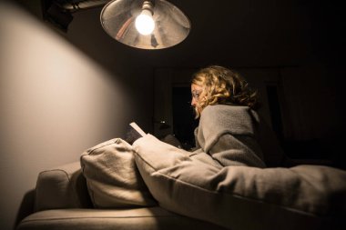 Stockholm, İsveç Bir kadın evinde kanepede kitap okuyor.