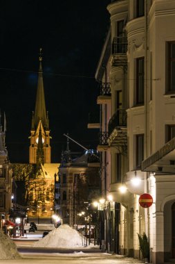 Sundsvall, İsveç geceleri şehir merkezindeki Gustav Adolf Kilisesi ve Kyrkogatan ya da CHurch Caddesi 'ndeki kar yığınları.