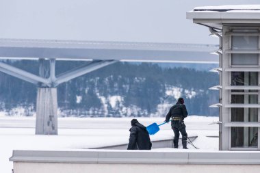 Sundsvall, İsveç. İki adam bir binanın çatısından buz ve kar kaldırıyor..
