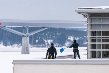 Sundsvall, İsveç. İki adam bir binanın çatısından buz ve kar kaldırıyor..